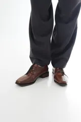 Zapato de charol negro de cuero vacuno con textura grabada tipo reptil, punta cuadrada y cordones al tono.