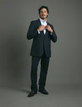 Traje de corte clásico compuesto por saco de dos botones y pantalón de vestir a juego. Diseño tradicional en color negro.