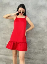 Vestido corto rojo de satén con breteles finos que se atan en los hombros y falda con volados.
