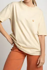 Remera color arena de algodón peinado, corte oversize y manga corta. Estampado pequeño de una concha en el pecho.