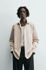 Camisa slim fit color beige, confeccionada en tejido de algodón, con cuello italiano y manga larga con puño de botón. Cierre frontal de botonadura.