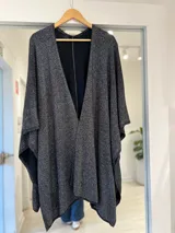 Ruana negra con hilo brillante lurex, de diseño amplio y abierto al frente.