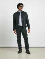 Campera capitoneada de color azul oscuro, con cierre frontal de metal y botones a presión. Presenta bolsillos laterales y en el pecho con cierres metálicos.