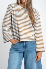 Remera de manga larga con cuello redondo, confeccionada en algodón con elastano. Presenta un diseño de rayas horizontales en color azul marino sobre fondo blanco.