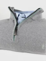 Buzo gris de hilo con cuello alto y medio cierre con cremallera roja.