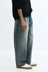 Jean de cinco bolsillos en denim de algodón rígido, color azul claro con efecto desgastado. Modelo de corte holgado de cadera a bajo con piernas redondeadas extraamplias y pliegues al tobillo. Cintura clásica con cierre y tiro bajo.