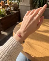 Pulsera de cadena fina con baño de oro, adornada con piedras naturales en tonos rosado y gris.