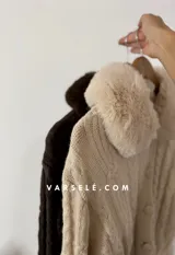 Saco tejido de punto con diseño de ochos, cuello con detalle de piel sintética, cierre frontal con botones al tono y mangas largas.