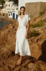 Vestido midi blanco con cuello camisero, escote en V, mangas cortas y falda plisada. Incluye cinturón con hebilla forrada.