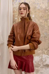 Chaqueta de cuero estilo bomber, con cuello alto, puños y cintura de tejido de punto acanalado. Presenta cierre frontal con cremallera y dos bolsillos laterales con solapa.