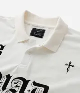 Remera de corte boxy confeccionada en algodón, con cuello polo y cierre frontal de botones. Presenta un diseño estampado en el frente con el número 93, una cruz y la palabra MAD en tipografía gótica.