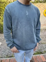 Buzo azul con efecto lavado, cuello redondo y logo bordado en el pecho.