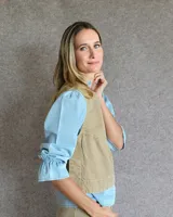 Chaleco de corte recto y largo a la cintura, confeccionado en denim con estampado de rayas verticales en tonos azul y blanco. Presenta cuello redondo y costuras visibles que definen su estructura.
