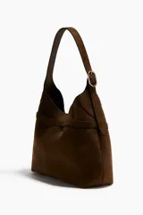 Cartera tipo hobo de diseño slouchy, color marrón, con correa de hombro ajustable y detalle de tira fina frontal con cierre de mosquetón metálico.