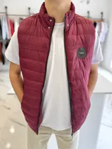 Chaleco puffer de nylon color bordó, con cuello alto, cierre frontal y bolsillos. Cuenta con un parche redondo con la inscripción "TURK" en el pecho.