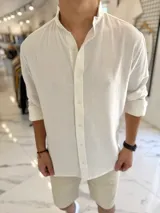 Camisa oversize de lino color blanco, con cuello mao, manga larga y cierre frontal de botones.