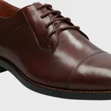 Zapato de vestir formal Hush Puppies modelo Jazz Brown, confeccionado en cuero marrón con diseño tipo oxford, cordones tono sobre tono y costuras decorativas.