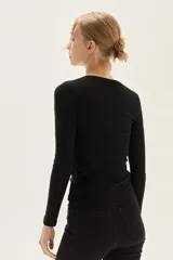 Top negro de manga larga, confeccionado en tela de lurex con calce al cuerpo y escote cuadrado.