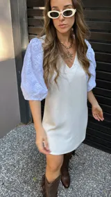 Vestido corto color crudo, con escote en V y mangas 3/4 abullonadas con detalles de calado.