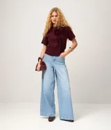 Remera femenina de manga corta color bordó, con cuello redondo y una aplicación figurativa en forma de lazo en la parte delantera, hecha en tejido fruncido que crea relieve. Confeccionada en algodón certificado BCI.