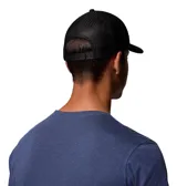 Gorro tipo trucker de la marca Columbia, color negro, con paneles traseros de malla para mayor ventilación. Presenta el logo de la marca bordado en el frente y un parche con el logo en el lateral. Cuenta con cierre trasero ajustable a presión.