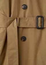 Trench coat largo oversize de color verde militar, con cierre de doble botonadura, trabillas en los hombros, cuello camisero de pana, cinturón con hebilla y trabillas ajustables en los puños.