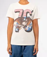 Remera de tejido suave color marrón con lavado especial, mangas cortas y cuello redondo. Presenta terminaciones con efecto desgastado en cuello, mangas y ruedo. Estampado frontal con el número "76" con diseño de bandera estadounidense, un águila calva con una cinta que dice "American Love" y estrellas.