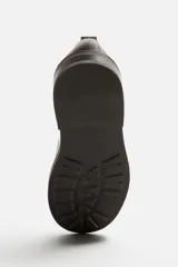 Zapato tipo blucher fabricado en piel de alta calidad, con cordonera de cinco pasados, horma redonda y suela a tono con ligero tacón.