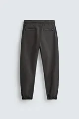 Pantalón tipo jogger de corte slim fit, confeccionado en tejido de algodón con elasticidad. Presenta cintura elástica ajustable con cordón, bolsillos frontales, bolsillos traseros de vivo y bajos con puños elásticos.
