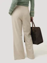 Pantalón tiro medio de lino orgánico y viscosa color beige, con corte recto y aberturas frontales en el dobladillo. Cuenta con cierre de botón en la cintura y bolsillos laterales.
