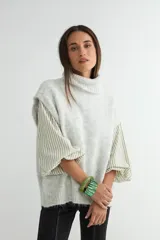 Chaleco de punto gris con cuello alto, diseño sin mangas y corte holgado.