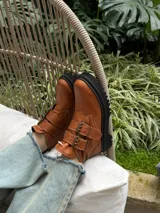 Botas cortas negras de cuero sintético con plataforma y suela track. Presentan dos correas con hebillas doradas y tirador trasero.