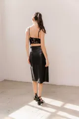 Pollera midi de eco cuero color beige, de corte recto y tiro alto, con costuras verticales decorativas y detalle de cinturón fino con flecos.