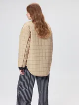 Campera reversible capitoneada con cierre frontal. Un lado es de color negro y el otro es de color beige, ambos con diseño acolchado. Cuenta con cuello redondo, mangas largas y bolsillos laterales.