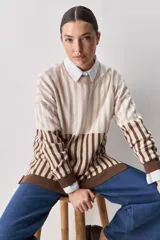 Sweater de tejido jacquard con diseño de rayas verticales en tonos rojo, blanco y azul. Presenta cuello redondo, hombros caídos y puños en contraste de color azul.