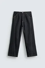 Jeans de denim oscuro, corte ancho (baggy fit) y tiro medio, con costura central girada en el frente de ambas piernas. Presenta pespuntes en color caramelo.