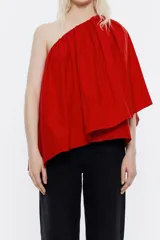 Blusa roja de tafeta con un hombro descubierto, escote recto con volantes y corte holgado.
