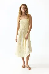 Vestido midi amarillo con estampado floreado, cuerpo fruncido elástico, breteles finos y escote cuadrado.