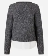 Suéter de punto jaspeado en color gris oscuro, con cuello redondo y mangas largas. Presenta un diseño integrado con una camisa blanca debajo, creando un efecto de capas superpuestas.