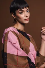 Sweater holgado con diseño de rombos en tonos marrón, negro y rosado, con detalles de lurex en las líneas divisorias. Presenta cuello redondo, mangas largas con puños acanalados y un corte relajado.