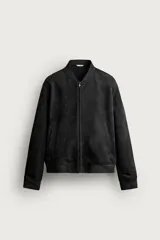 Cazadora bomber de corte relajado, confeccionada en tejido efecto ante de color negro, con cuello, puños y dobladillo de canalé elástico. Cuenta con bolsillos laterales de vivo y cierre frontal con cremallera.