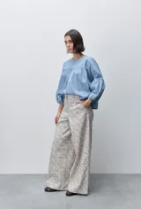 Pantalón de tiro alto con silueta amplia y piernas rectas, confeccionado en algodón con estampado floral. Cuenta con cierre frontal de botón y cremallera, y bolsillos laterales funcionales.