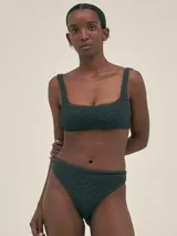 Conjunto de bikini negro con textura, compuesto por un corpiño de corte recto con breteles anchos y una bombacha de tiro alto con cobertura total en la parte delantera y corte colaless en la parte trasera.