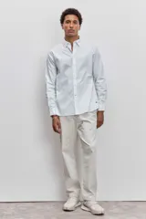 Camisa de manga larga en color celeste con estampado de rayas verticales finas, cuello abotonado y cierre frontal con botones.