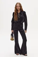 Pantalón de lino negro con corte acampanado, tiro medio-alto, pretina ancha, cierre frontal oculto y bolsillos laterales.