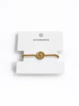 Pulsera de eslabones tipo bolitas con dije central circular grabado en tono dorado.
