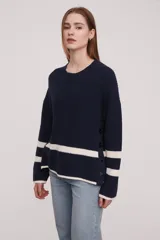 Sweater de punto en color azul marino con rayas horizontales blancas en la parte inferior y en las mangas. Presenta un diseño de cuello redondo, corte holgado y detalle de botones decorativos en el lateral.