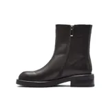 Bota corta de cuero negro con diseño minimalista, costura central visible en el empeine y suela plana de goma con pequeño taco cuadrado.