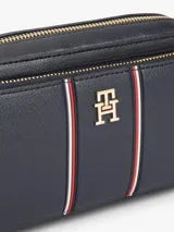 Cartera bandolera Tommy Hilfiger de color azul marino, con acabado granulado, cierre de cremallera superior, compartimento principal y bolsillo exterior con cremallera. Incluye correa extraíble para el hombro, detalles distintivos con franjas verticales y la insignia del monograma TH en metal dorado en la parte delantera.