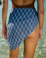 Pareo triangular de seda con estampado de monograma en tonos azules. Presenta un diseño ligero y fluido, ideal para usar sobre trajes de baño.